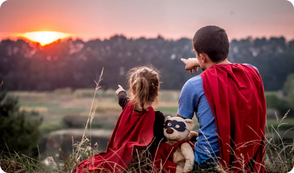 niña con su papa de superheroe sentados en el pasto padres exitosos